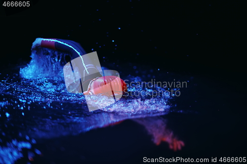 Image of real triathlon athlete swimming in dark night