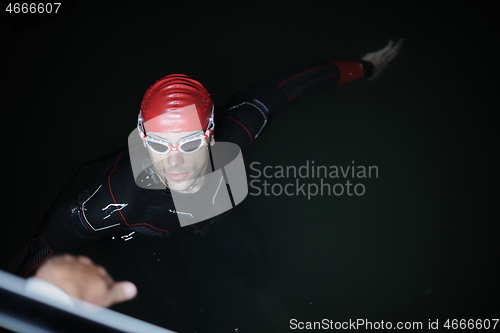 Image of authentic triathlete swimmer having a break during hard training on night