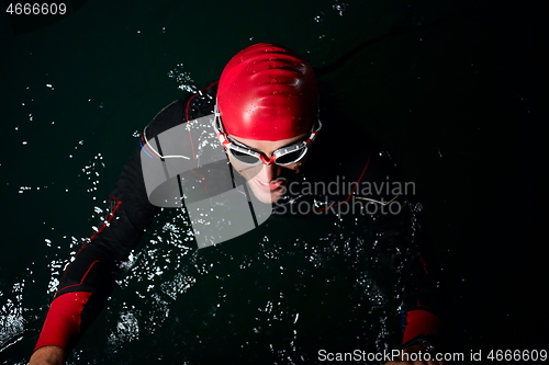 Image of triathlon athlete swimming in dark night wearing wetsuit