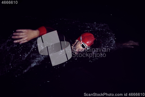 Image of triathlon athlete swimming in dark night wearing wetsuit