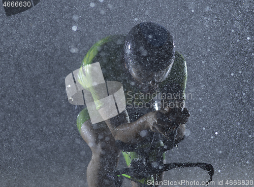 Image of triathlon athlete riding bike on rainy night