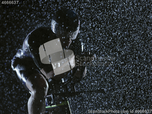 Image of triathlon athlete riding bike on rainy night