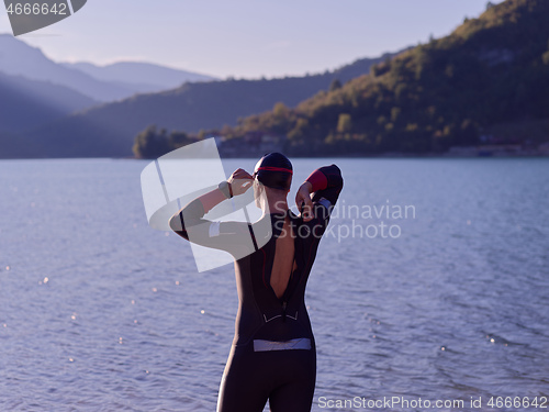 Image of authentic triathlon athlete getting ready for swimming training on lake