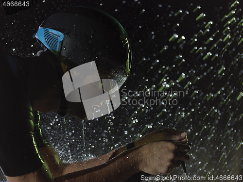 Image of triathlon athlete riding bike on rainy night