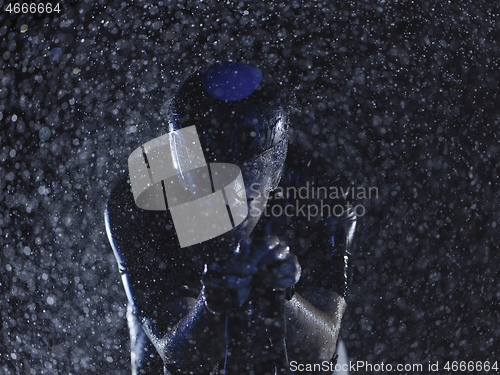 Image of triathlon athlete riding bike on rainy night