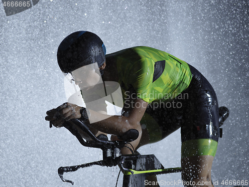 Image of triathlon athlete riding bike on rainy night