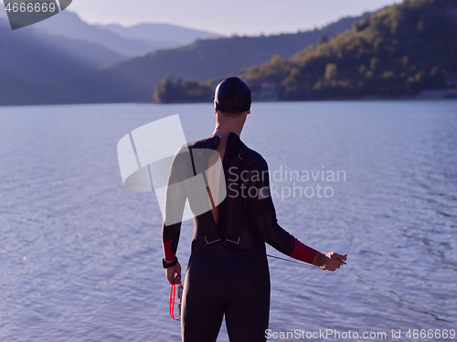 Image of authentic triathlon athlete getting ready for swimming training on lake