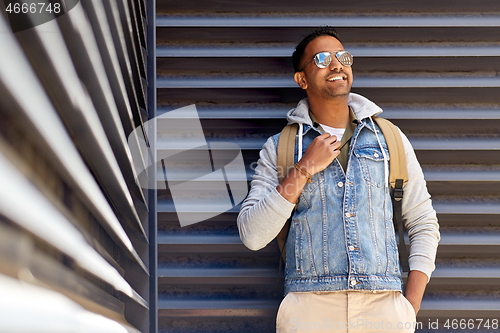 Image of smiling indian man with backpack on city street