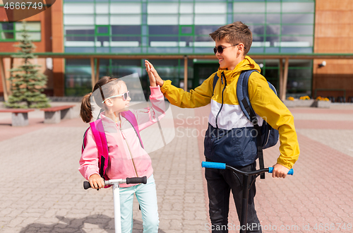 Image of school kids riding scooters and making high five