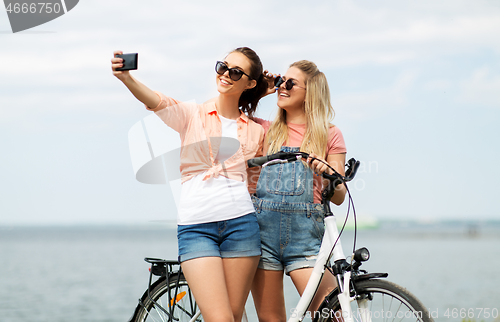 Image of teenage girls with bicycle taking selfie in summer