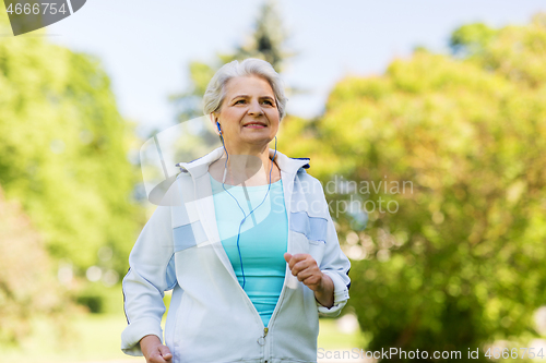 Image of senior woman with earphones running in summer park