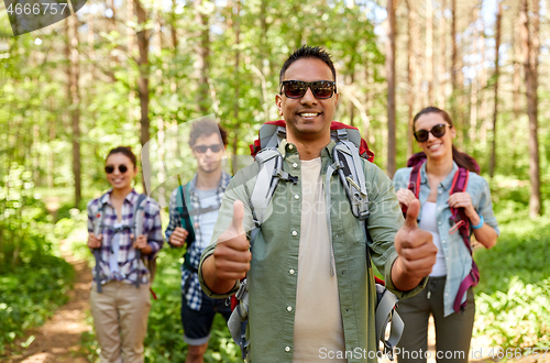 Image of friends with backpacks showing thumbs up in forest