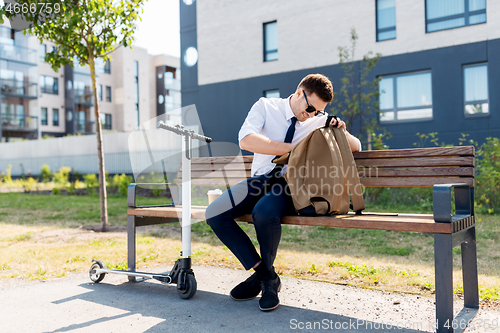 Image of businessman with bag, scooter and coffee in city