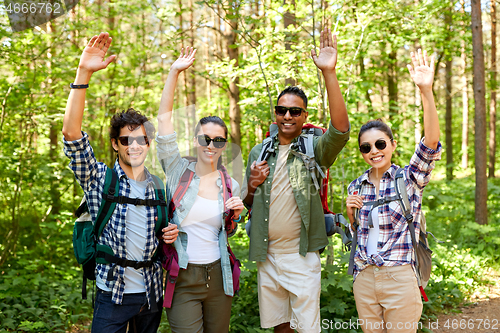 Image of group of friends with backpacks hiking in forest