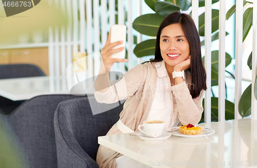 Image of asian woman taking selfie by smartphone at cafe