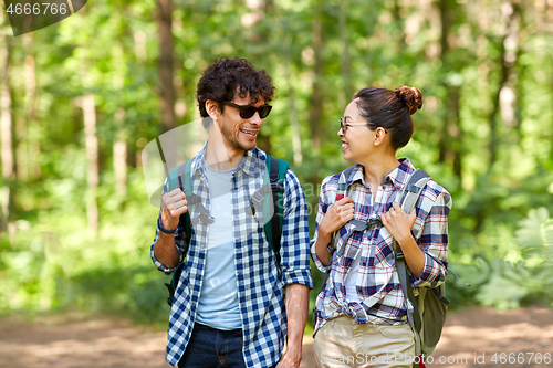 Image of mixed race couple with backpacks hiking in forest