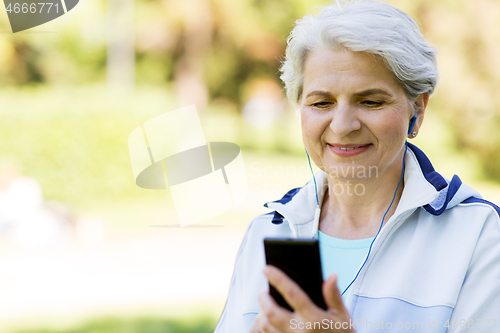 Image of sporty senior woman with earphones and smartphone