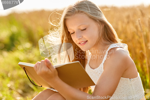 Image of smiling girl writing to diary on cereal field