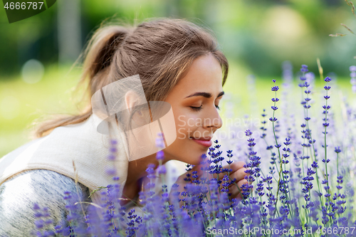 Image of young woman smelling lavender flowers in garden