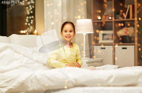 Image of happy little girl in bed at home at night