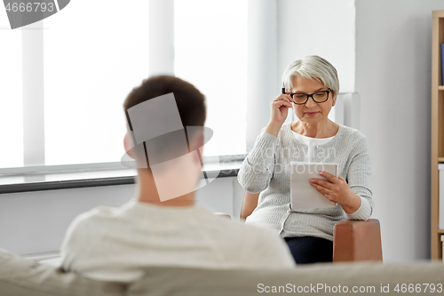 Image of senior woman psychologist and young man patient