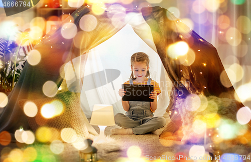 Image of little girl with tablet pc in kids tent at home