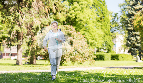 Image of senior woman running along summer park