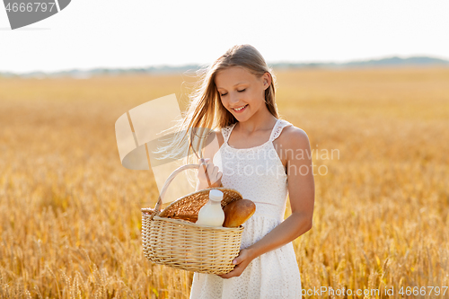 Image of girl with bread and milk in basket on cereal field