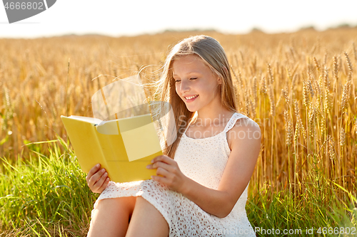 Image of smiling young girl reading book on cereal field