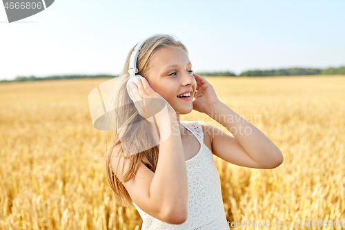 Image of happy girl in headphones on cereal field in summer