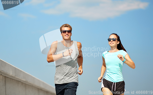 Image of couple in sports clothes running outdoors