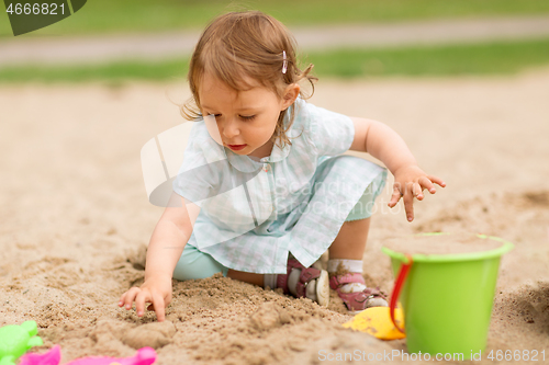 Image of little baby girl plays with toys in sandbox