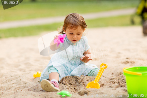 Image of little baby girl plays with toys in sandbox