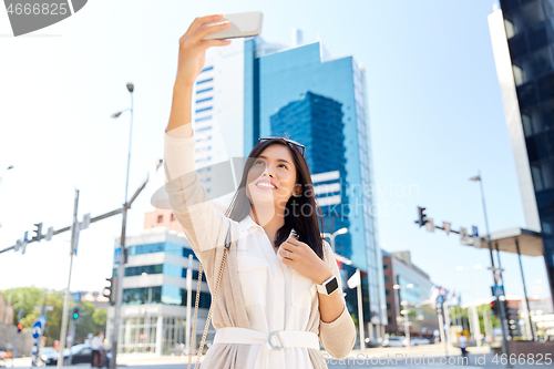 Image of asian woman taking selfie by smartphone in city