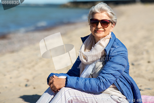 Image of happy senior woman in jacket on beach