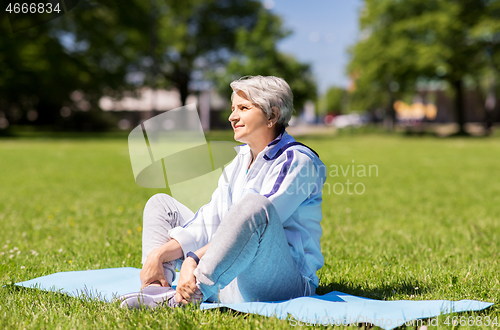 Image of happy senior woman exercising at summer park