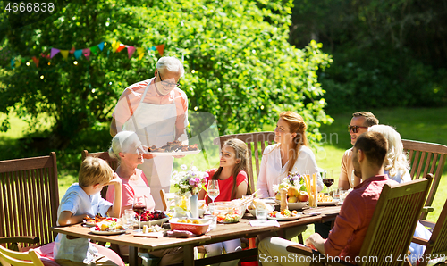 Image of family having dinner or barbecue at summer garden