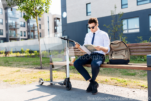 Image of businessman with file and scooter sitting on bench