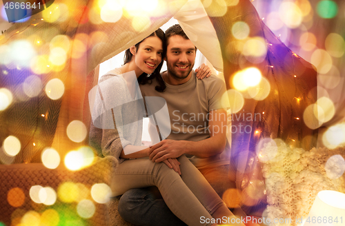 Image of happy couple in kids tent at home