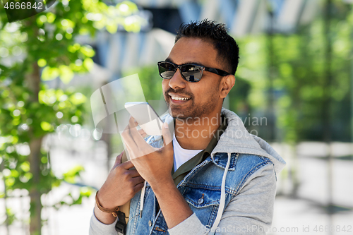 Image of man recorving voice message on smartphone in city