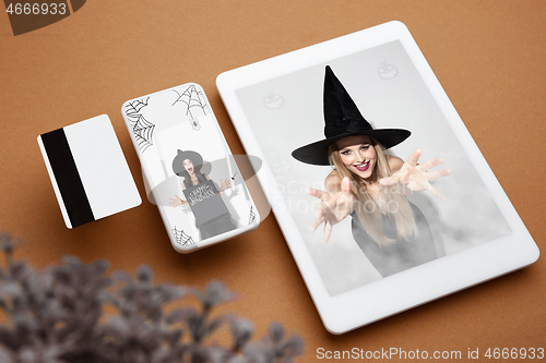 Image of Young woman in hat as a witch on device screen background, mock up with copyspace