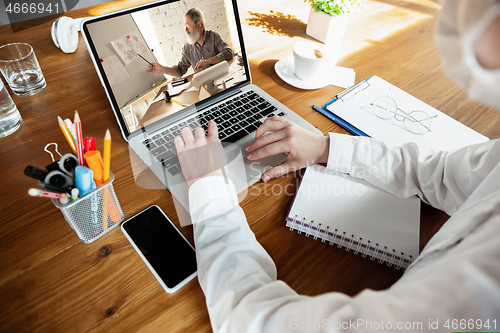 Image of Young doctor working online with laptop, has online conference with colleague from workplace