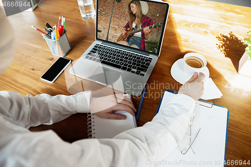 Image of Young doctor working online with laptop, watching online music concept with smiling singer