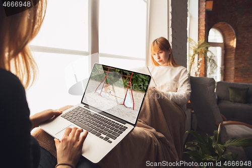 Image of Two friends watching online competition, TV or cinema together with devices