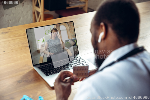 Image of Young doctor working online with laptop, has online conference with colleague from workplace