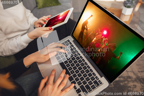 Image of Two friends watching online party, TV or cinema together with devices