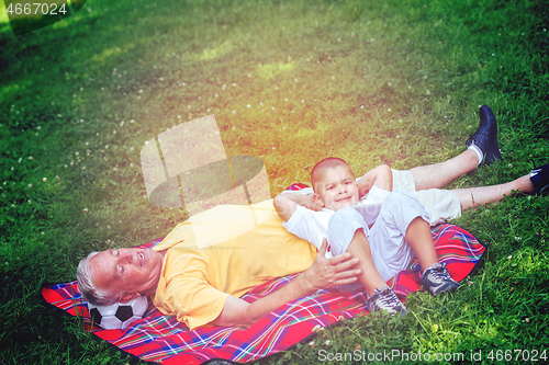 Image of grandfather and child in park using tablet