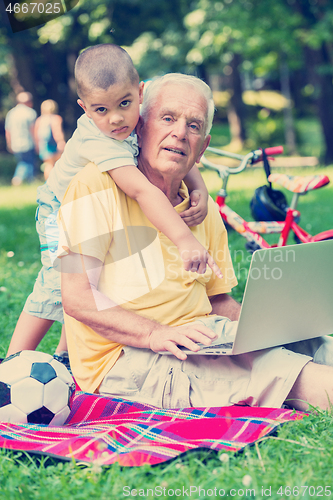 Image of grandfather and child using laptop