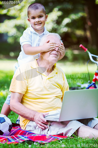 Image of grandfather and child using laptop