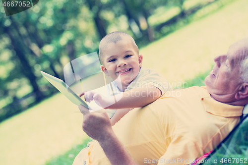 Image of grandfather and child in park using tablet